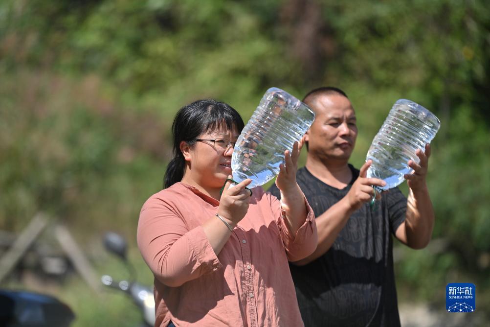 楊寧（左）在查看村民剛剛采集的水樣，為山泉水引水工程做準(zhǔn)備（10月8日攝）。新華社記者 黃孝邦 攝